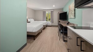 A modern hotel room with two beds, a desk, a flat-screen TV, and a large window with curtains. - Echo Suites Extended Stay By Wyndham Johnson City Medical Cr (Johnson City)