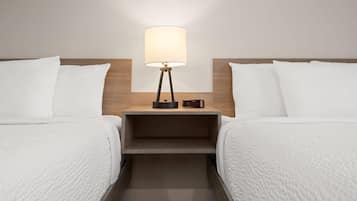 Ein Hotelzimmer mit zwei Betten, einem Nachttisch mit Lampe und einem kleinen Tisch.