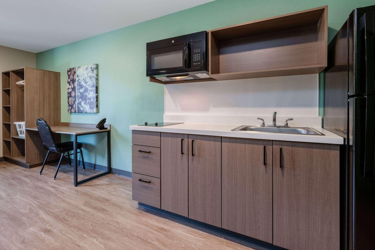 A compact kitchen with a microwave, sink, and cabinets.