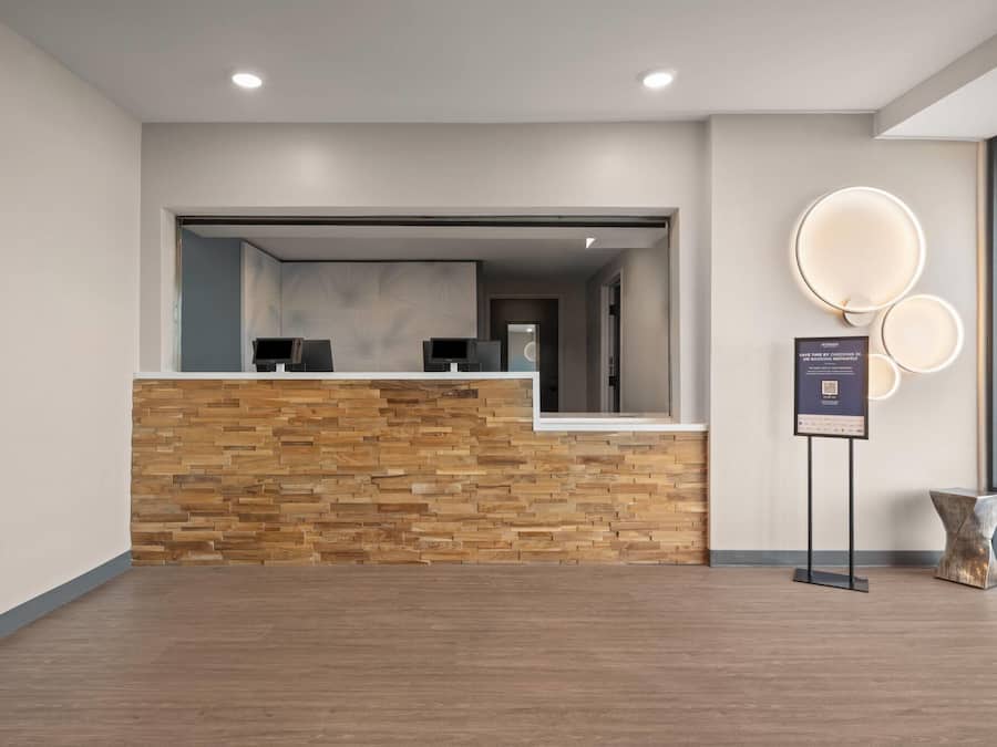 A reception area with a wooden reception desk, a glass partition, and a wall-mounted sign.