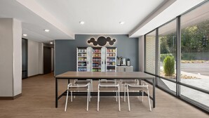 A modern library with a long table and white chairs, surrounded by bookshelves. - Echo Suites Extended Stay By Wyndham Johnson City Medical Cr (Johnson City)