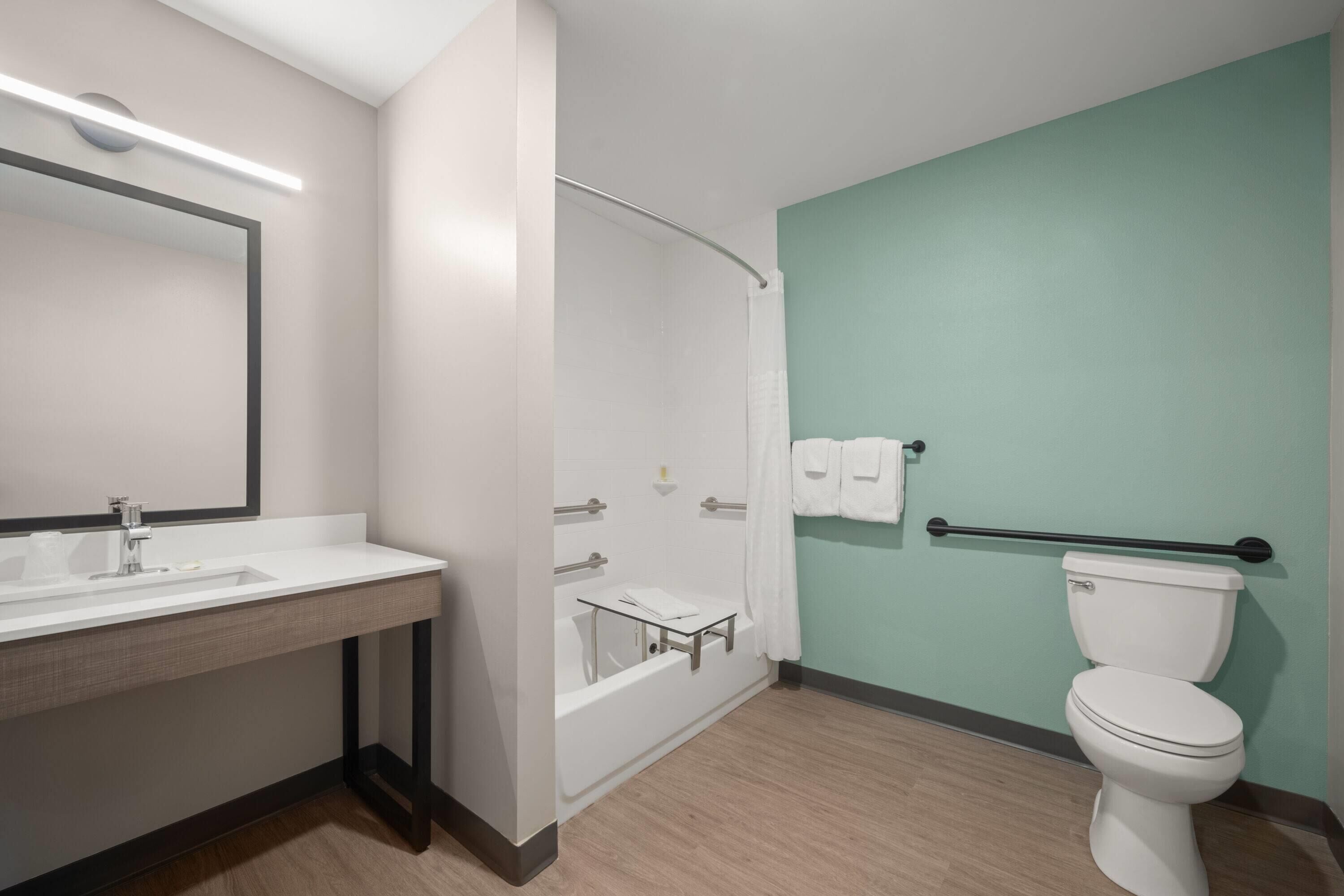 Ein modernes Badezimmer mit Waschbecken, Spiegel, Badewanne und Toilette.