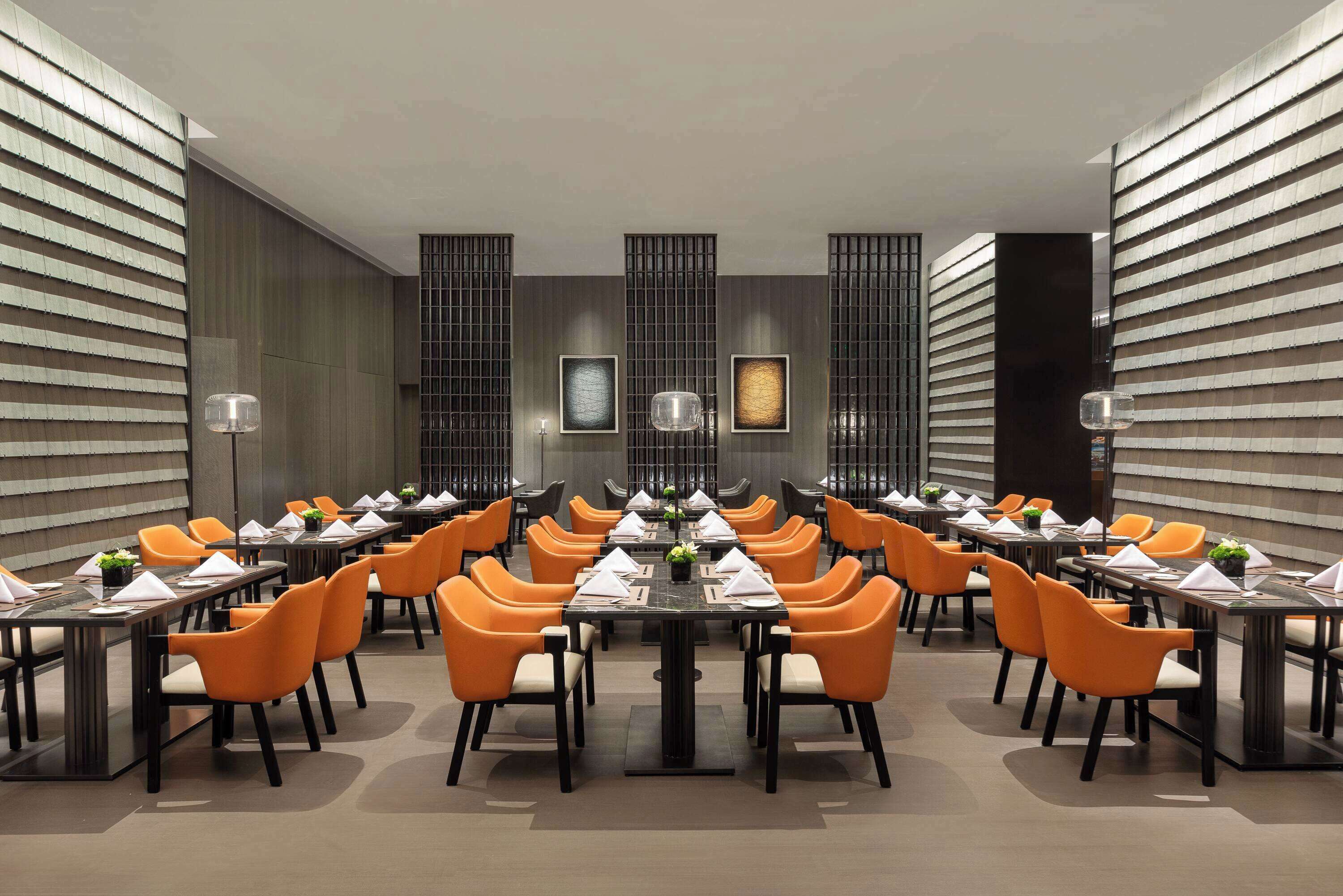 A conference room with multiple tables and chairs, arranged in a U-shape, with a modern design and neutral color scheme.