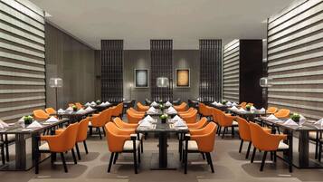 A conference room with multiple tables and chairs, arranged in a U-shape, with a modern design and neutral color scheme.