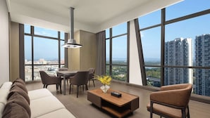 A modern living room with a sofa, a coffee table, and a chair, with large windows offering a city view. - Wyndham Grand Chengdu East (Chengdu)