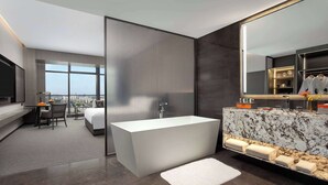 A modern hotel bathroom with a large bathtub, a vanity with a marble countertop, and a large mirror. - Wyndham Grand Chengdu East (Chengdu)