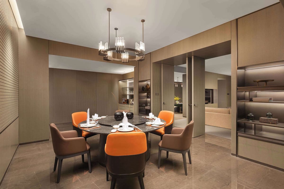 A modern dining area with a round table, six chairs, and a chandelier.