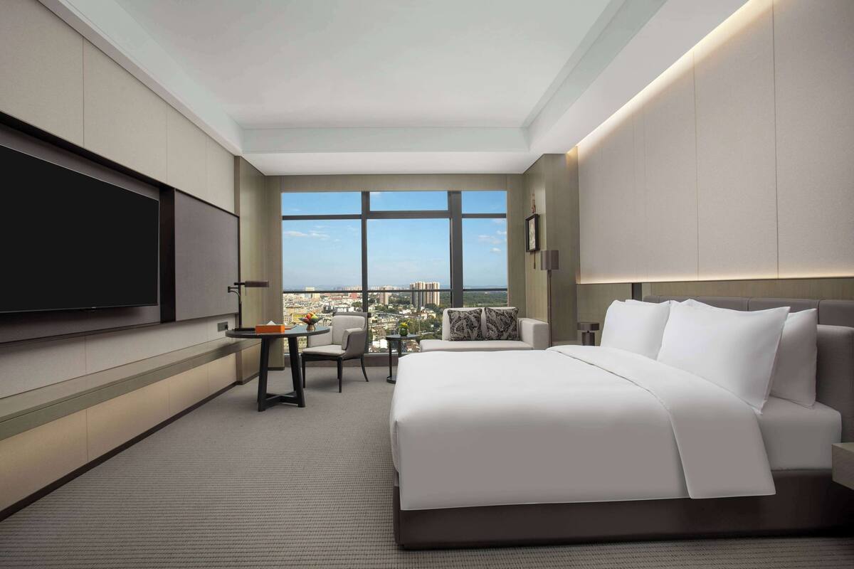 A modern hotel room with a large bed, a desk, and a TV.