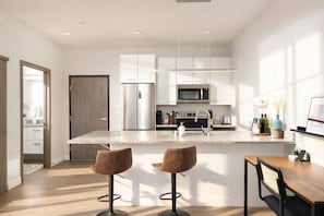 Una cocina moderna con una isla central, electrodomésticos de acero inoxidable y taburetes de bar.