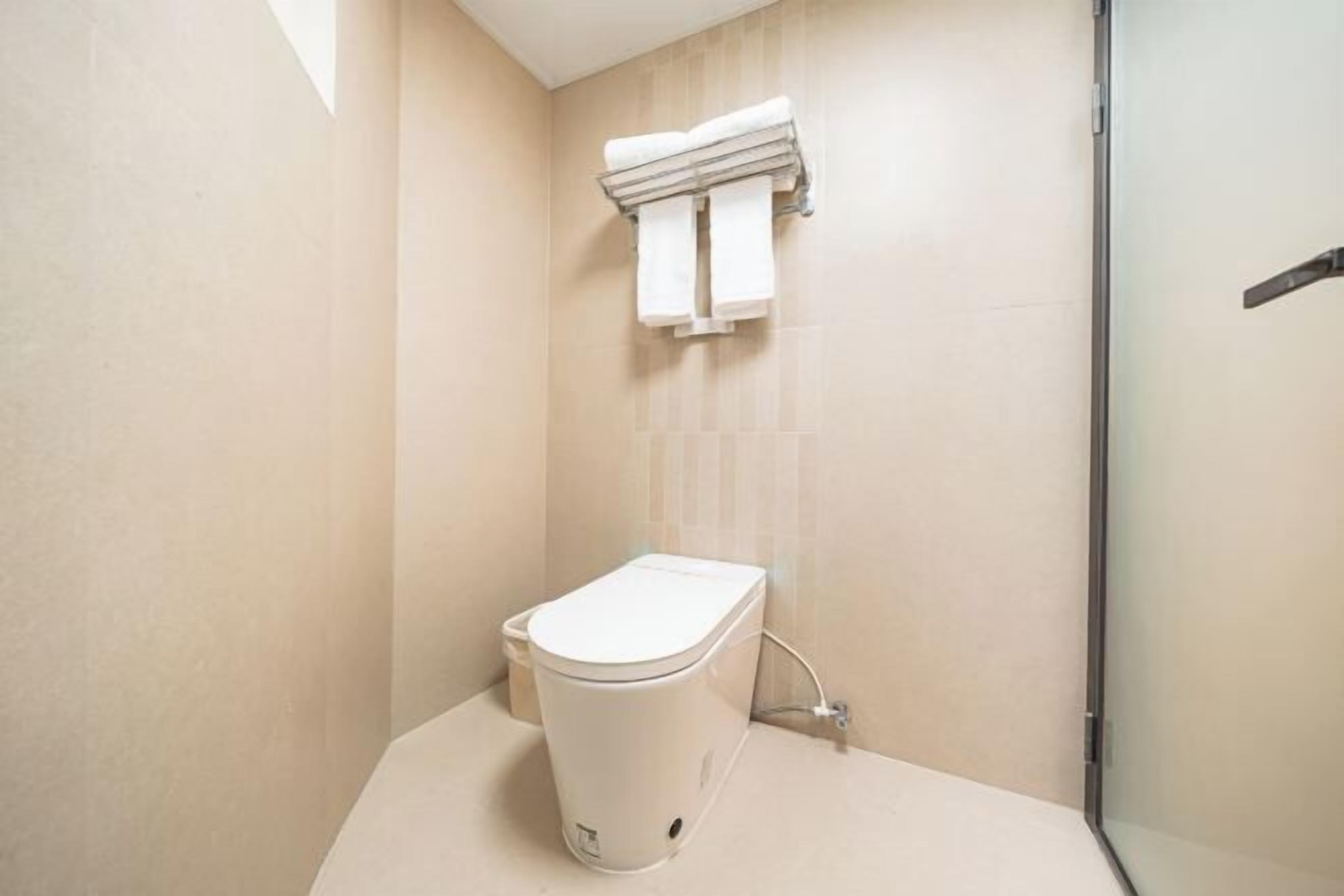 A modern bathroom with a toilet, a towel rack, and a glass shower enclosure.
