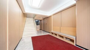 Un pasillo moderno con alfombra roja, paredes de madera, un banco y una escalera que lleva a otra zona.