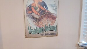 Een oude poster van een koppel op een boot, met de tekst 'Carefree Days Vashon Island Washington' op een muur.