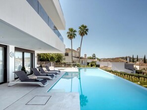 A modern poolside area with lounge chairs, a clear pool, and a view of the surrounding landscape. - Luxury Villa with Views Marbella  (Marbella)