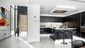 A modern kitchen with a central island, black cabinetry, and a large window. - Luxury Villa with Views Marbella  (Marbella)