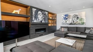 A modern living room with a large flat-screen TV, grey sofas, and artwork on the walls. - Luxury Villa with Views Marbella  (Marbella)