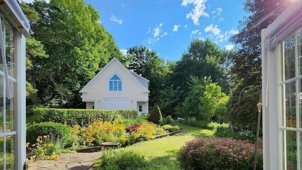 Un sendero conduce a una casa rodeada de exuberante vegetación y un jardín cuidado.