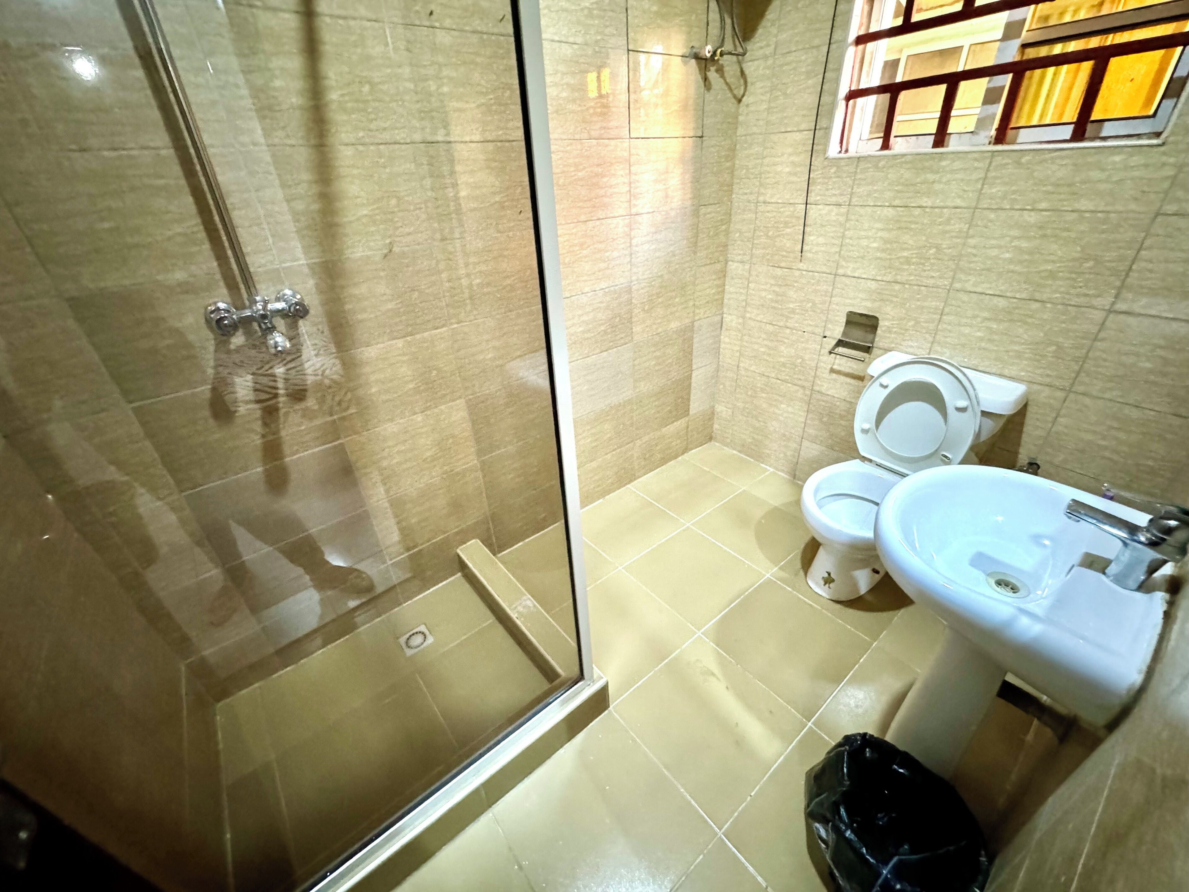 A bathroom with a glass-enclosed shower, a toilet, and a sink.
