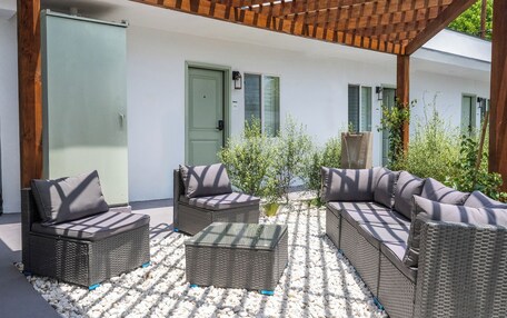 A covered outdoor seating area with wicker furniture and a stone-tiled floor.