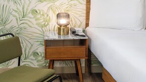 A hotel room with a bed, a nightstand with a lamp, a telephone, and a chair. - The LEEF Hotel (Glendale)