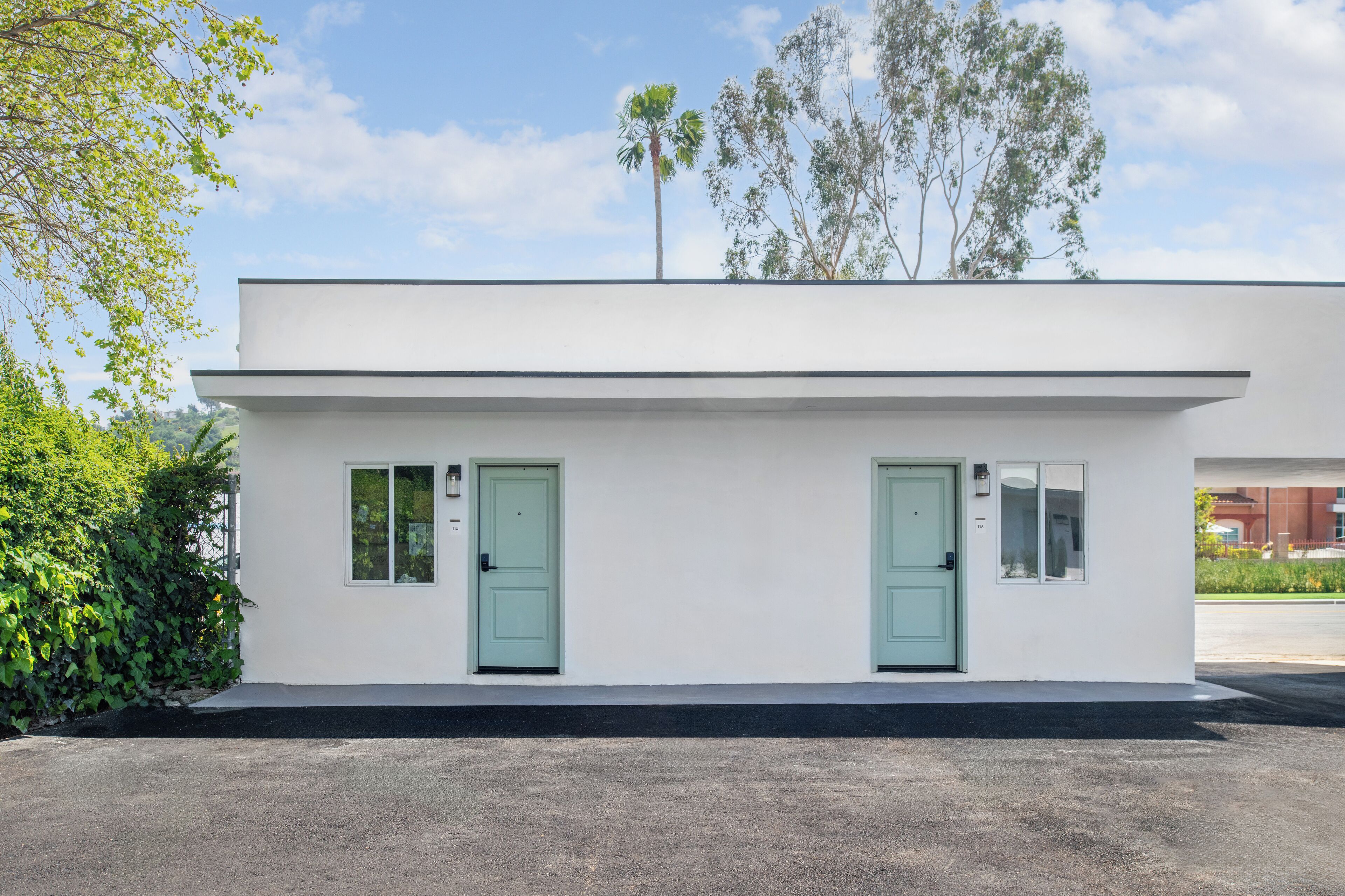 A modern building with two doors and windows, surrounded by greenery and trees.