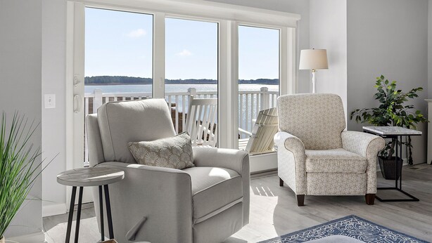 A balcony with a view of the water, two armchairs, a small table, and a lamp. - Bayfront Coastal Paradise | Pool | Beach Access (Bethany Beach)