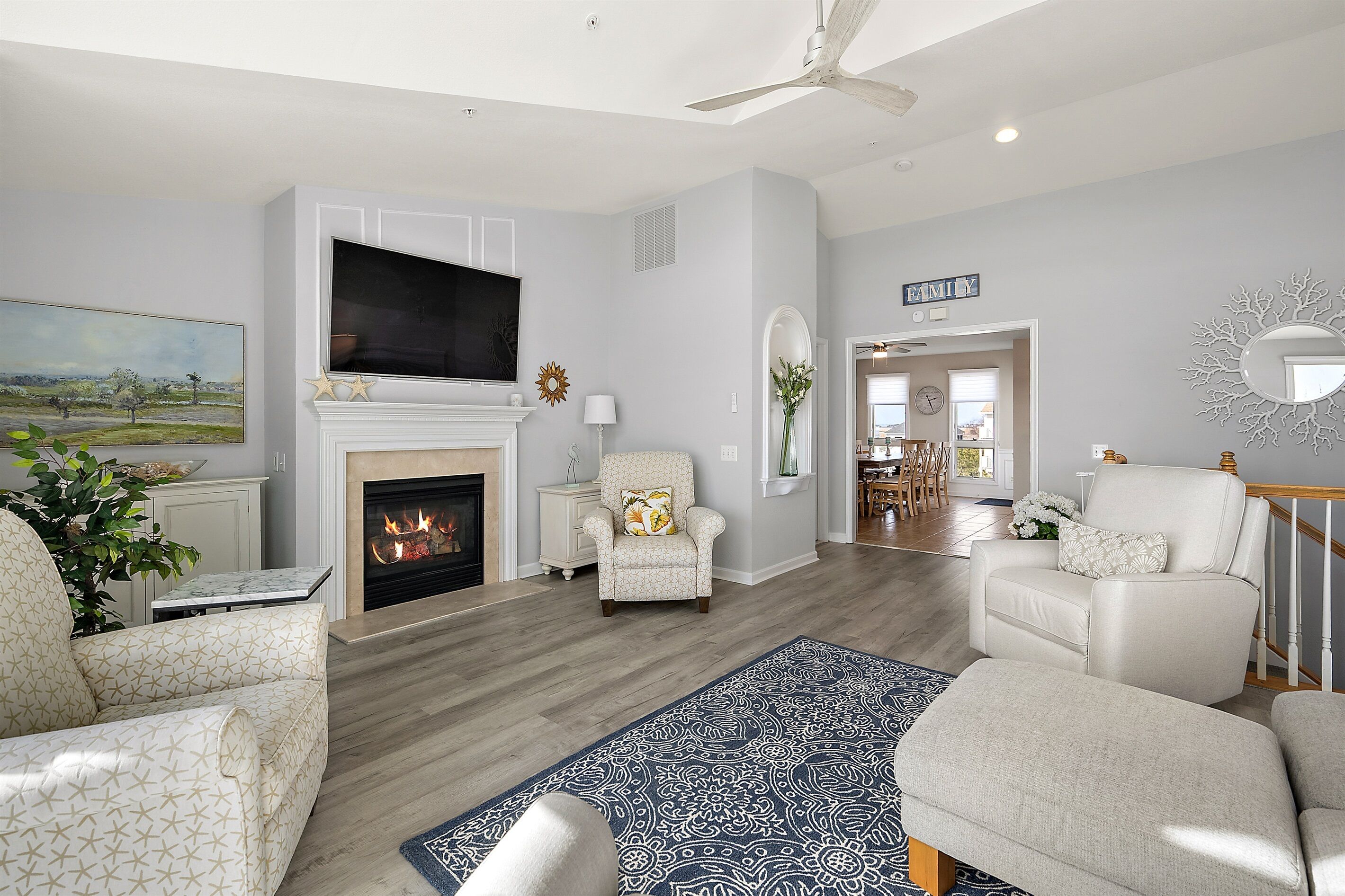 Una sala de estar con chimenea, televisor y una escalera que lleva a otra habitación.