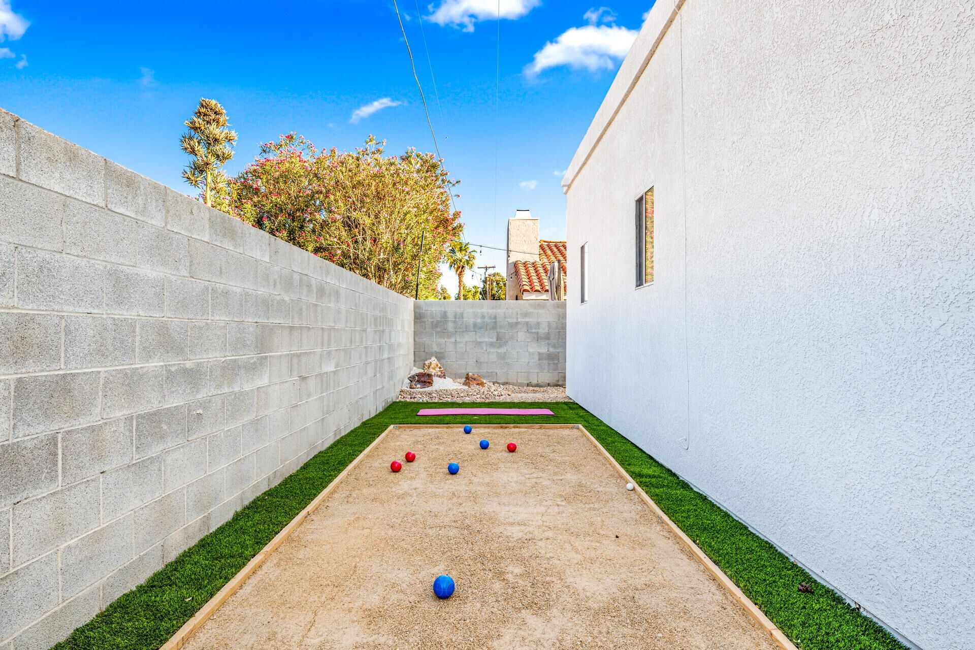 A courtyard with a croquet court, a concrete wall, and a building with a window.