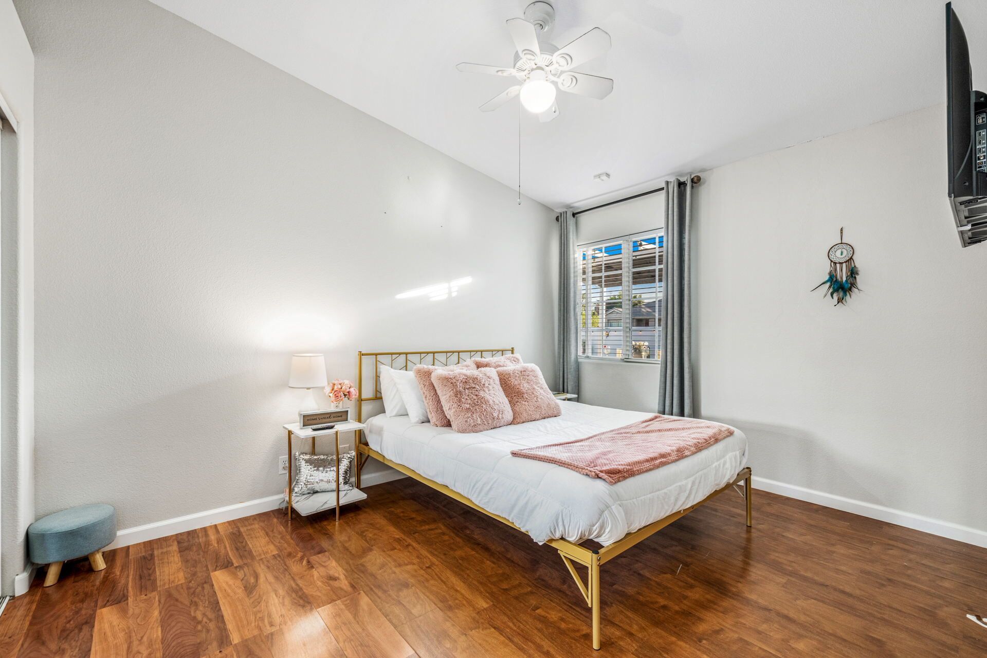 A bedroom with a bed, bedside table, lamp, and a ceiling fan.