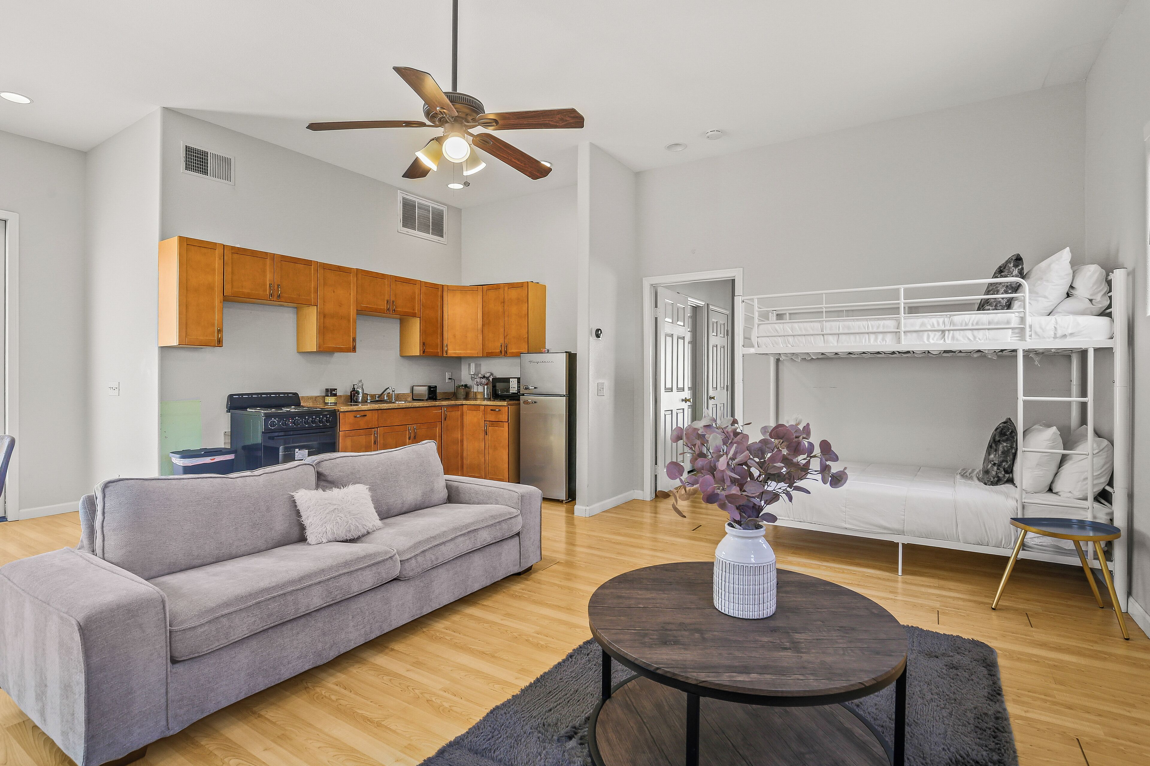 A modern living space with a sofa, a dining table, a kitchen area, and a bunk bed.