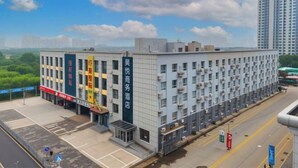 Ein mehrstöckiges Hotel mit modernem Design, mit einer auffälligen vertikalen Beschilderung in chinesischen Schriftzeichen, einer glatten Fassade und einem Parkplatz davor.