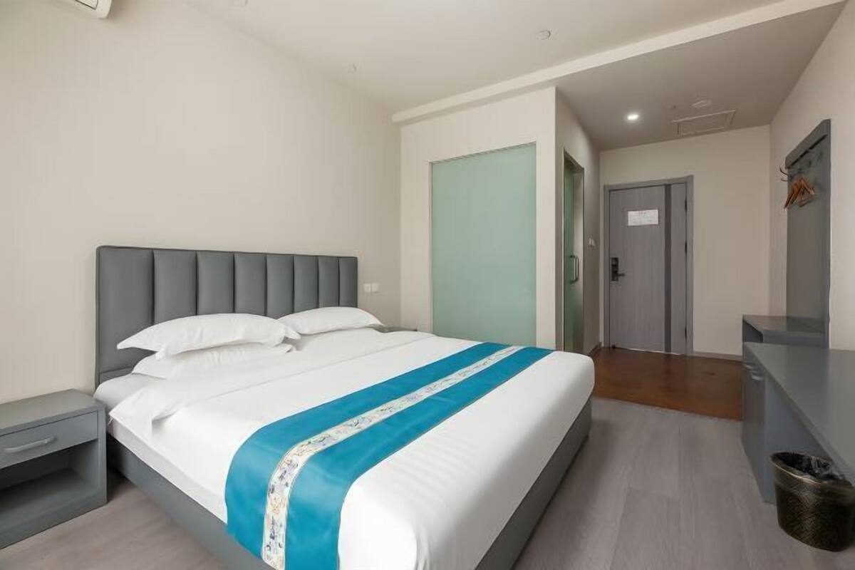 Une chambre d’hôtel avec un lit, une table de chevet, un bureau et une porte.
