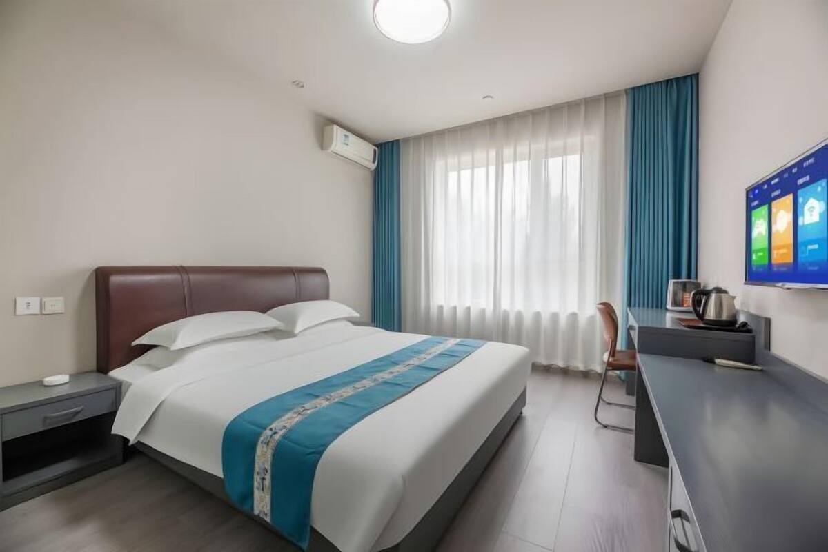 Une chambre d’hôtel équipée d’un lit, d’un bureau, d’une chaise, d’une télévision et d’un appareil de climatisation.