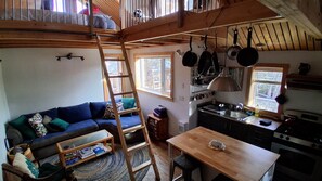 Acogedor interior de cabaña con habitación en entrepiso, comedor y cocina.