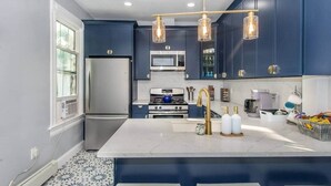 Une cuisine moderne avec des meubles bleu foncé, des appareils en acier inoxydable et un îlot en marbre.