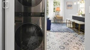 Une cuisine moderne dotée d’appareils électroménagers en acier inoxydable, d’un sol carrelé à motifs et donnant sur un coin repas avec une table et des chaises.
