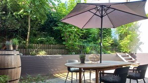 An outdoor patio with a round table and chairs, a large umbrella, and potted plants. - In the heart of Haltern (Haltern am See)