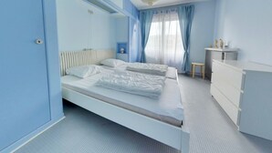 A bedroom with a bed, a dresser, a nightstand, and a window with curtains. - Apartment in Middelkerke With Sea View (Middelkerke)