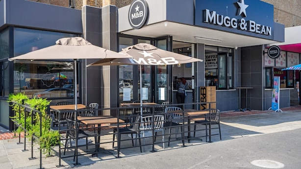 Un espace extérieur aménagé avec des tables et des chaises, situé devant un magasin M&B.
