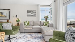 Ein modernes Wohnzimmer mit einem grauen Ecksofa, grünen Sessel und einem gemusterten Teppich.