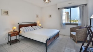 A bedroom with a bed, bedside tables, a chair, and a window with a view. - Charming 2 bedroom Apt/Balcony/Parking/by Marina+Shops (Antibes)