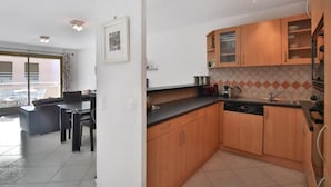 A modern kitchen with wooden cabinets, a black countertop, and a tiled backsplash. - Charming 2 bedroom Apt/Balcony/Parking/by Marina+Shops (Antibes)