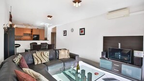 A modern living room with a leather sofa, a glass coffee table, and a flat-screen TV. - Charming 2 bedroom Apt/Balcony/Parking/by Marina+Shops (Antibes)