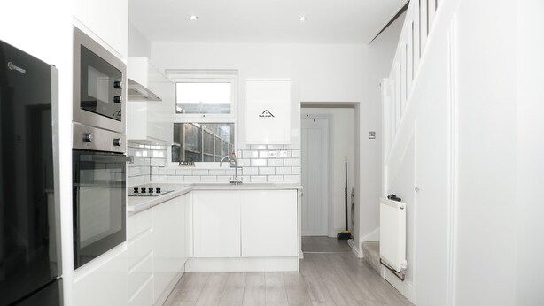 A modern kitchen with white cabinetry, a built-in oven, and a window above the sink. - 3 Bed-sleeps 7-garden-parking-town Centre (Dartford)