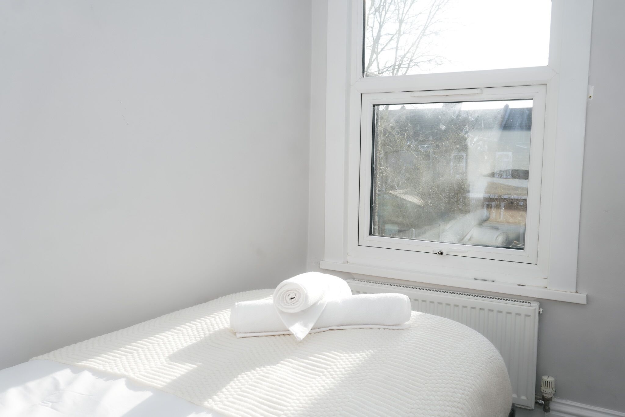 Un dormitorio con cama, ventana y radiador.