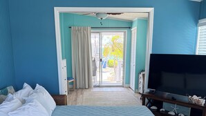 A bedroom with a large bed, a TV, and a view to the outside. - Canal front with open water views in Venture Out - Lot 529 (Cudjoe Key)
