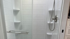 A small, enclosed shower area with a glass door, a toilet, and a blue bath mat. - Canal front with open water views in Venture Out - Lot 529 (Cudjoe Key)