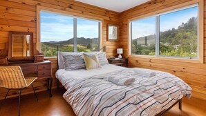 Un dormitorio con una cama grande, paredes de madera y vistas a un paisaje montañoso.