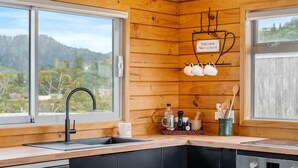 Una cocina moderna con paredes de madera, un lavamanos empotrado y vistas al exterior.