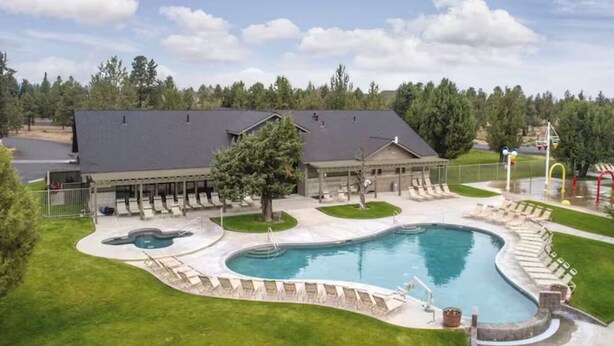 A large swimming pool with a curved design, surrounded by lounge chairs and a covered seating area.