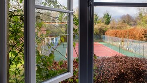 Ein Tennisplatz mit roter und grüner Belag, umgeben von einem Zaun und Bäumen.
